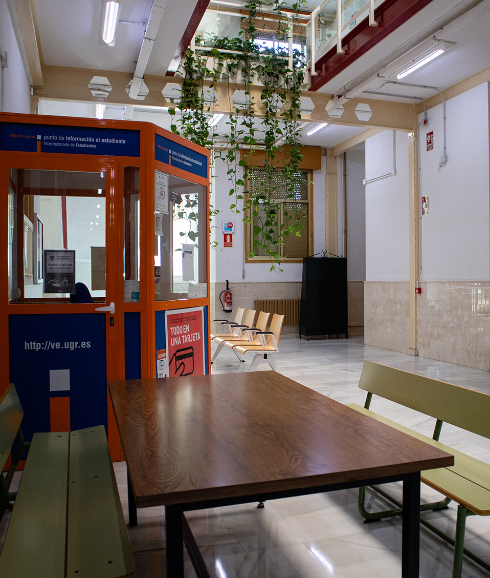 Interior de la facultad de psicología, con una mesa, bancos y punto de información